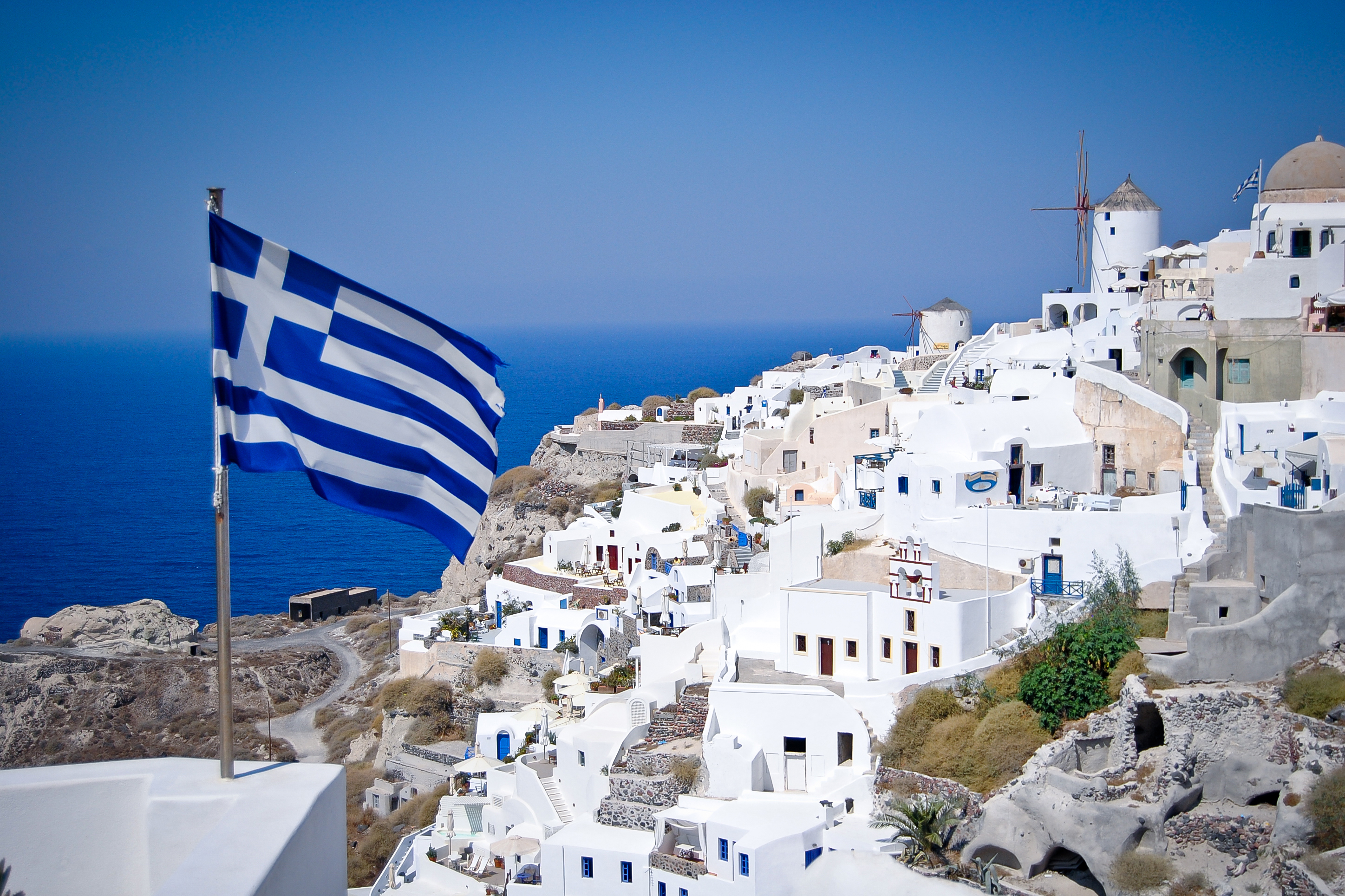 The Greek flag on the background of the coast symbolizes the Greek residence permit for investment