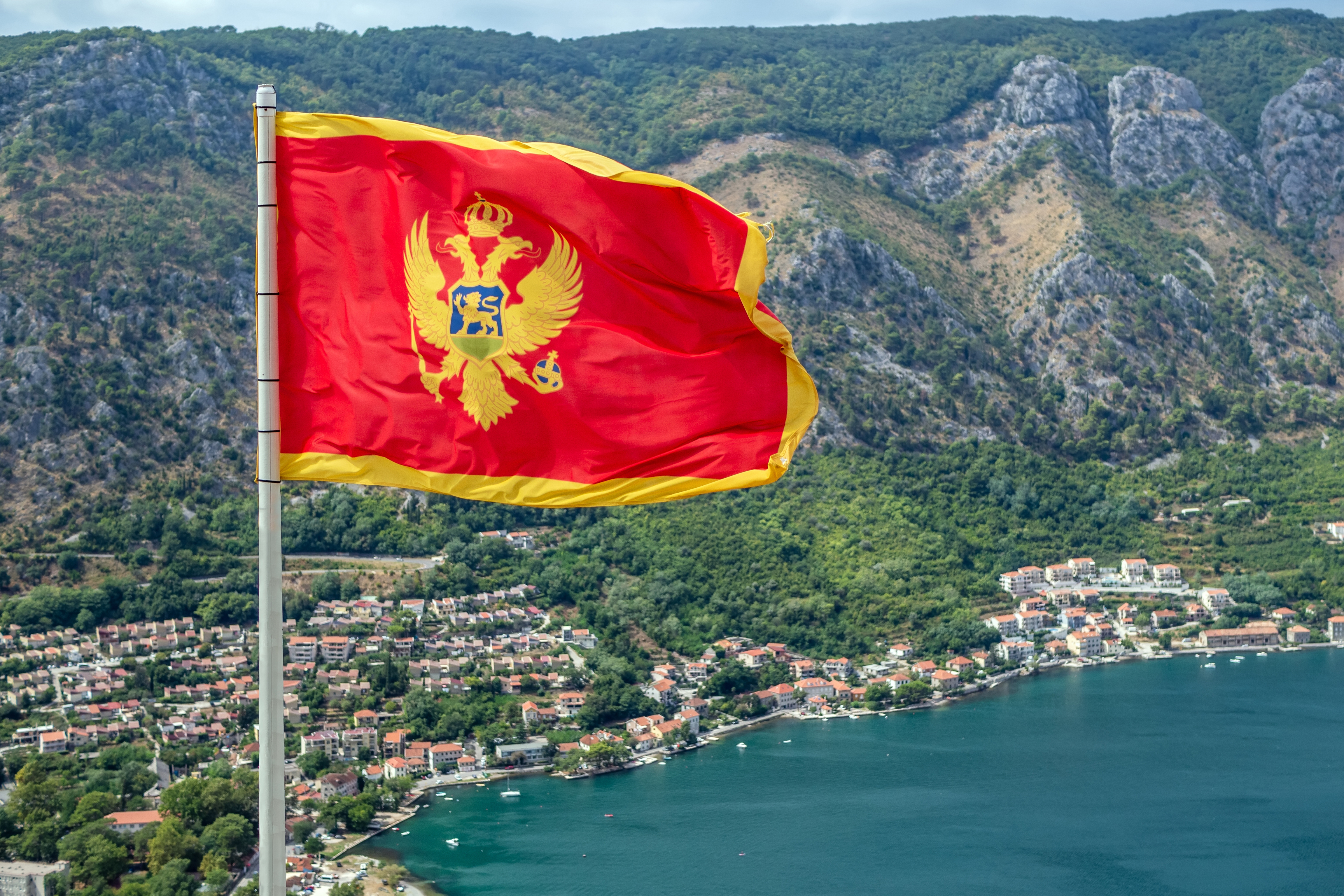 Flag on the background of Montenegro as a symbol of citizenship after obtaining a residence permit in Montenegro
