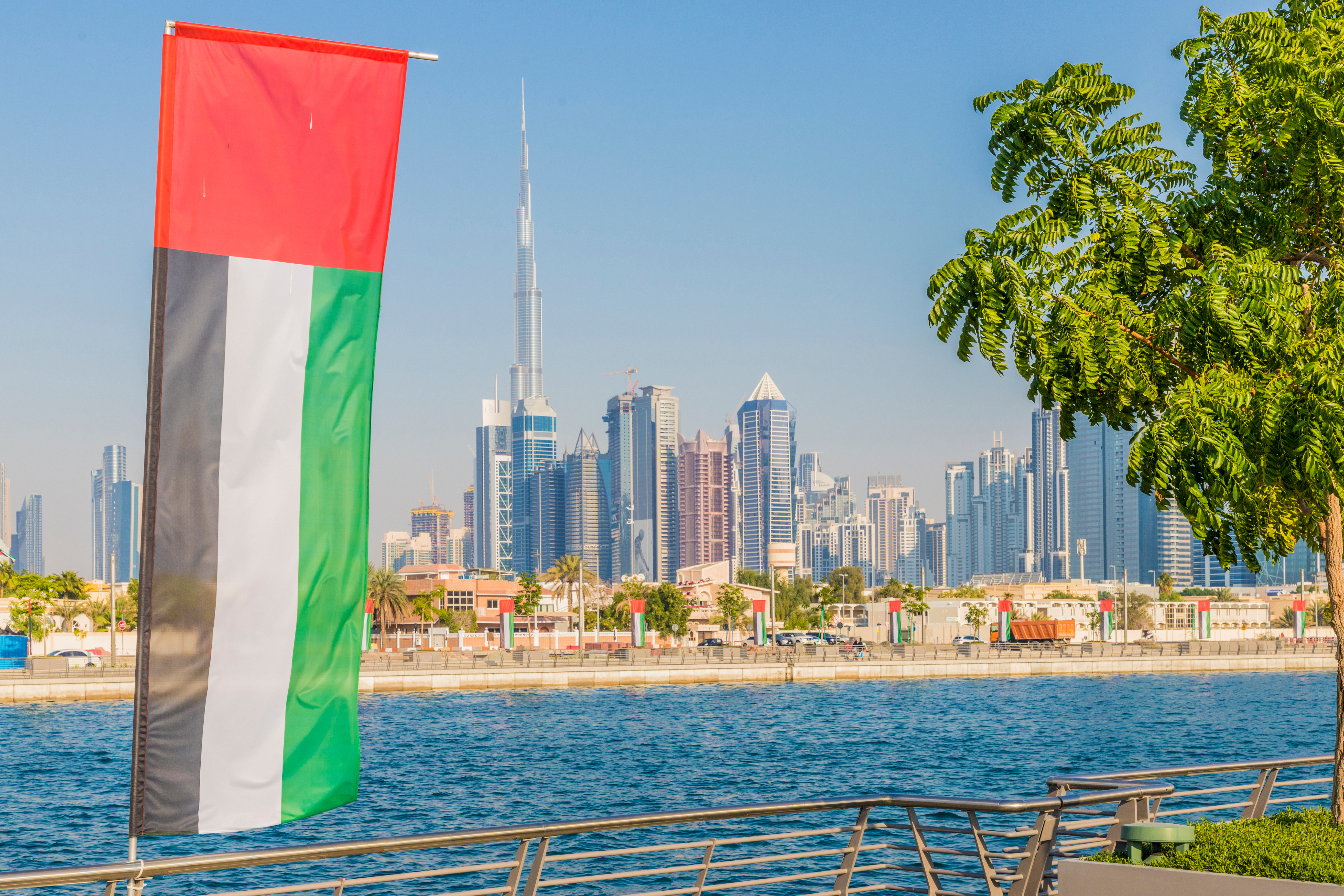 Flag against the background of the Emirati city of Dubai, where you can get a UAE residence permit